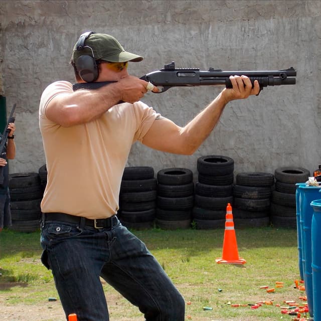 Alumno de TDU adoptando una posición de tiro defensivo con escopeta, manteniendo la guardia alta y el arma lista para el combate.