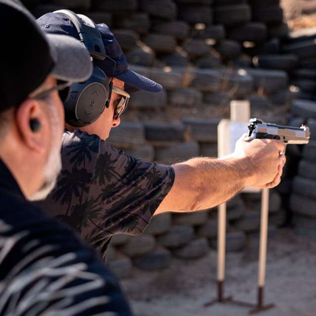 Instructor de tiro de TDU observando y corrigiendo los primeros disparos de un alumno en el curso de tiro inicial con pistola