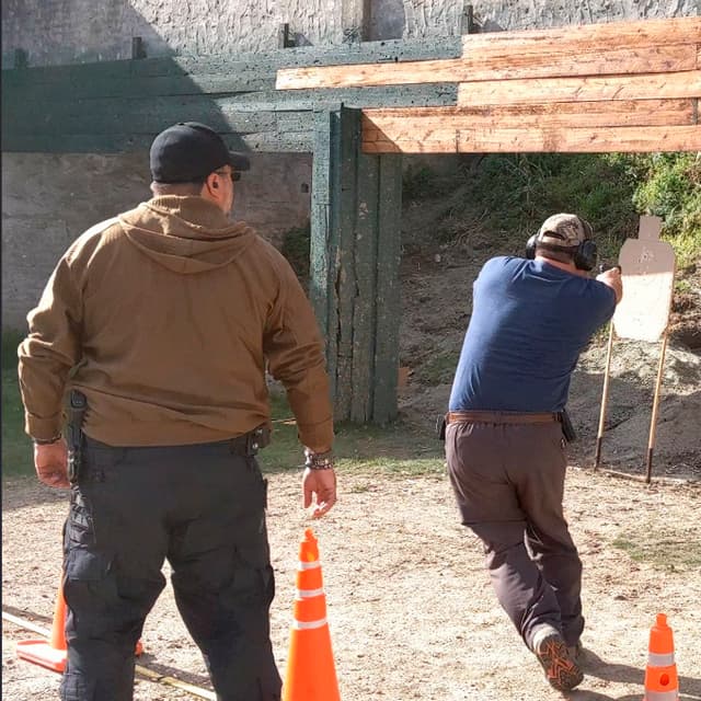 Instructor Jorge Chaves de TDU supervisando de cerca un ejercicio de tiro defensivo con pistola en el campo de entrenamiento.