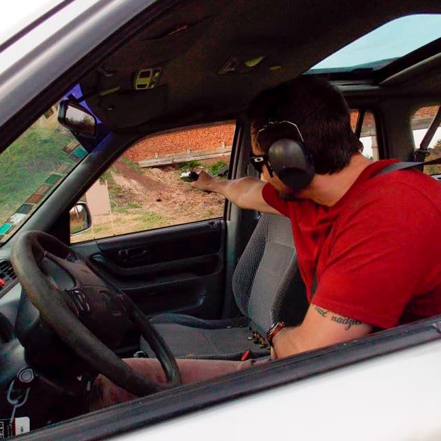 Alumno practicando un ejercicio de tiro defensivo con pistola desde el interior de un vehículo, simulando una situación de autoprotección en TDU.